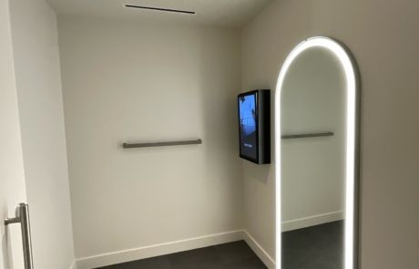 A dressing room with a large mirror and a television on the wall.