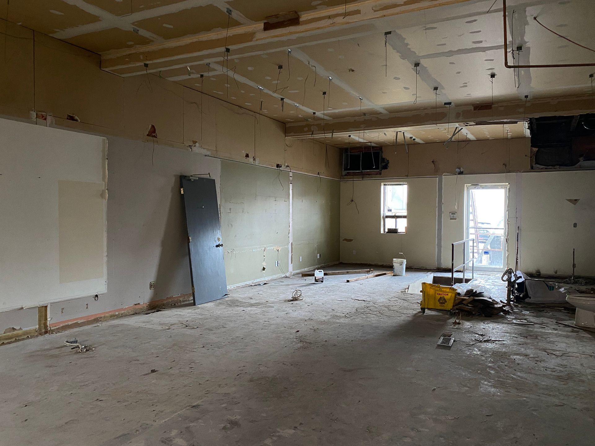 An empty room with a yellow bucket on the floor - Elgin, IL - Omni Commercial Group, Inc