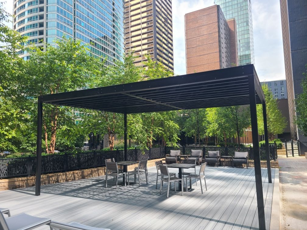A patio with tables and chairs under a canopy in the middle of a city.