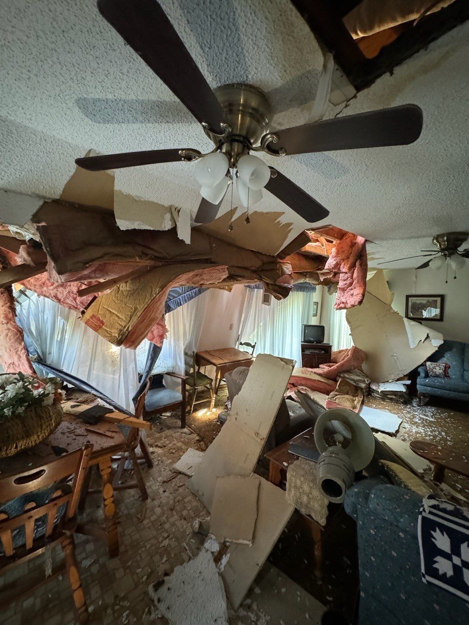 Interior of a room with a collapsed ceiling. Debris covers furniture and floors.