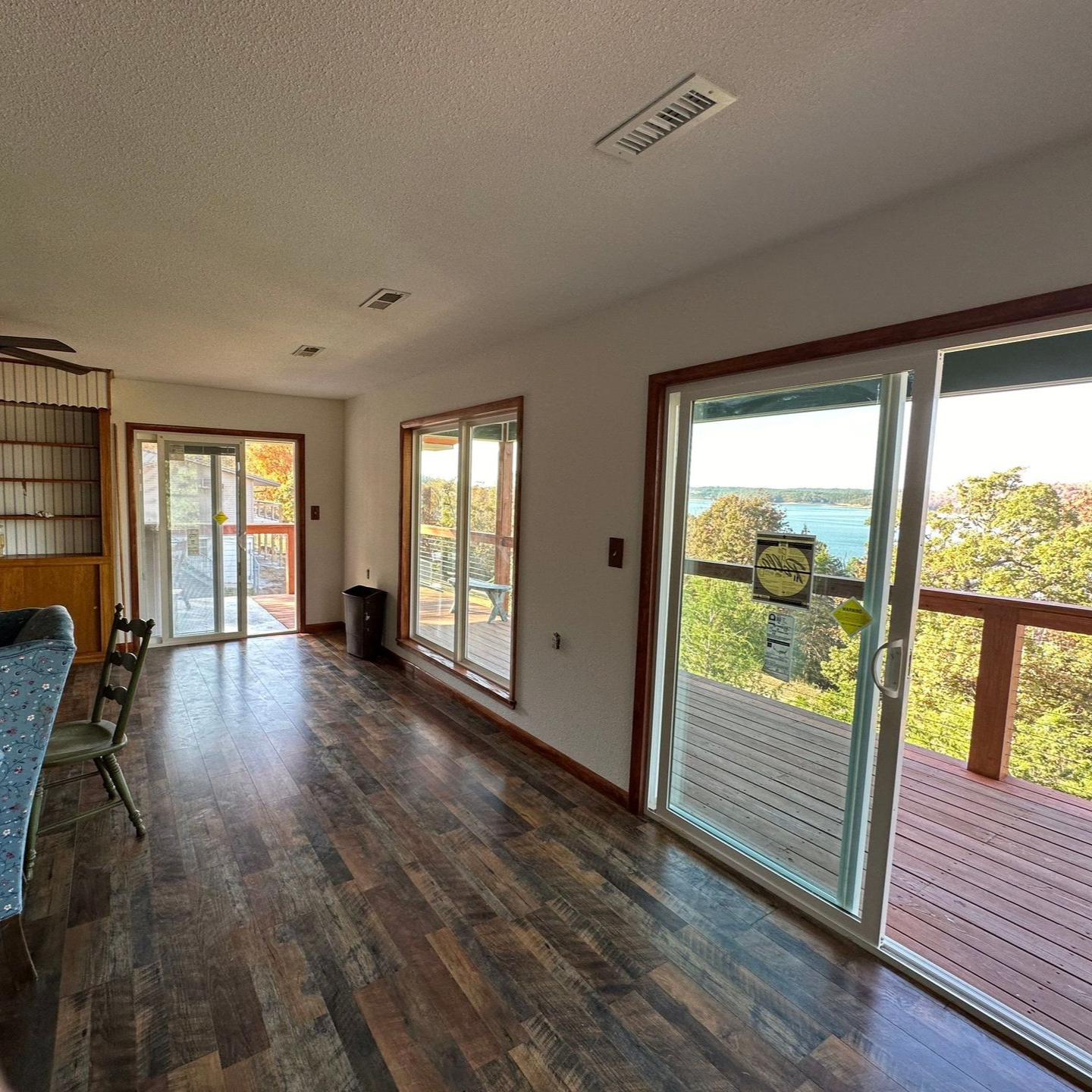 Living room with deck overlooking water, featuring wood floors, sliding glass doors, and a view.