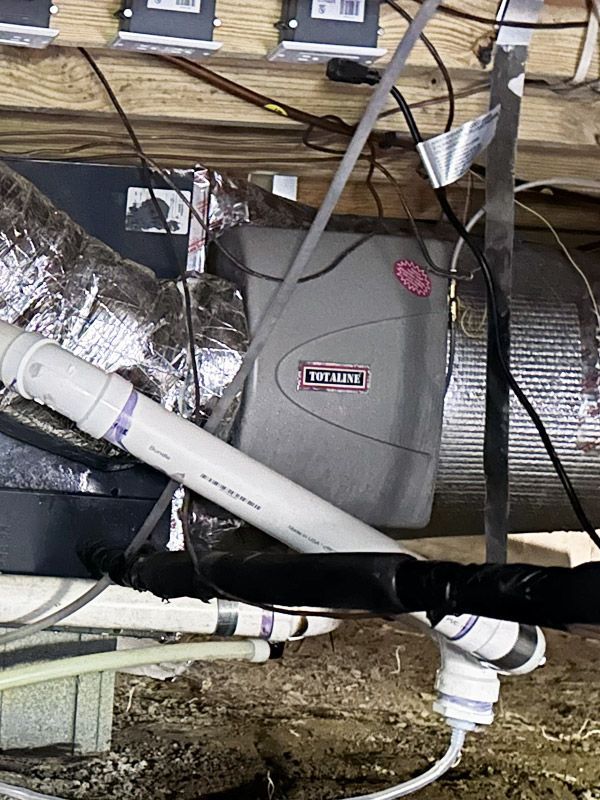 A humidifier is sitting under a ceiling in a basement.