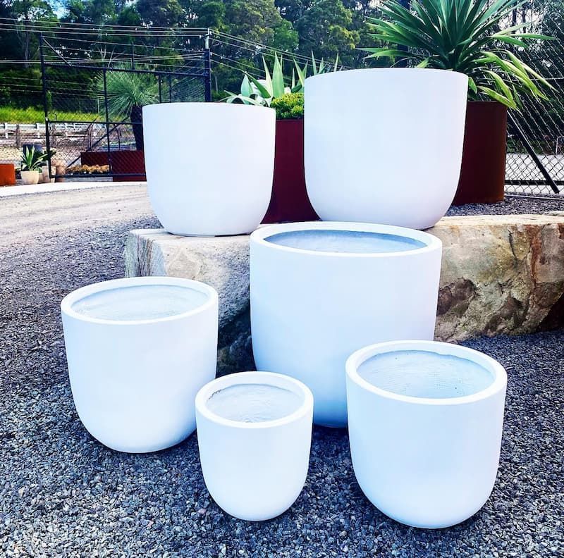 A Group Of White Pots Are Sitting On Gravel — Schutz Landscape and Garden Supplies in Jervis Bay, NSW