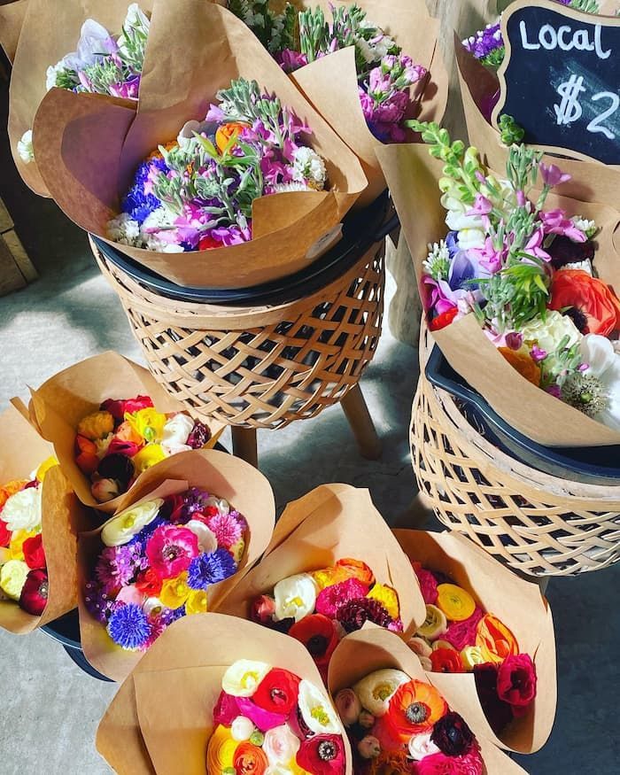 A Bunch Of Baskets Filled With Flowers And A Sign That Says Local — Schutz Landscape and Garden Supplies in Nowra, NSW