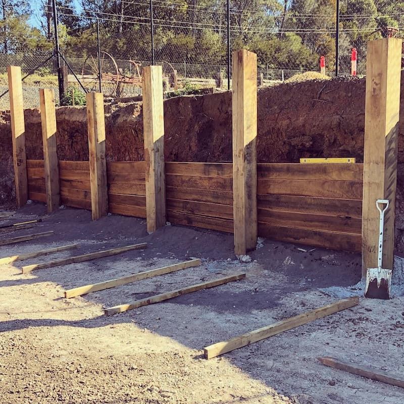 A Wooden Fence Is Being Built Next To A Pile Of Dirt And A Shovel — Schutz Landscape and Garden Supplies in Tomerong, NSW
