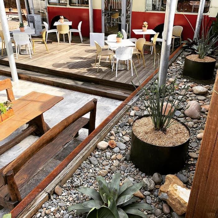 A Patio With Tables And Chairs Surrounded By Rocks And Plants — Schutz Landscape and Garden Supplies in Tomerong, NSW