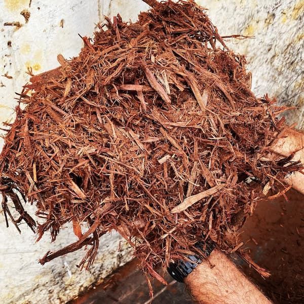 A Person Is Holding A Pile Of Wood Chips In Their Hands — Schutz Landscape and Garden Supplies in Tomerong, NSW
