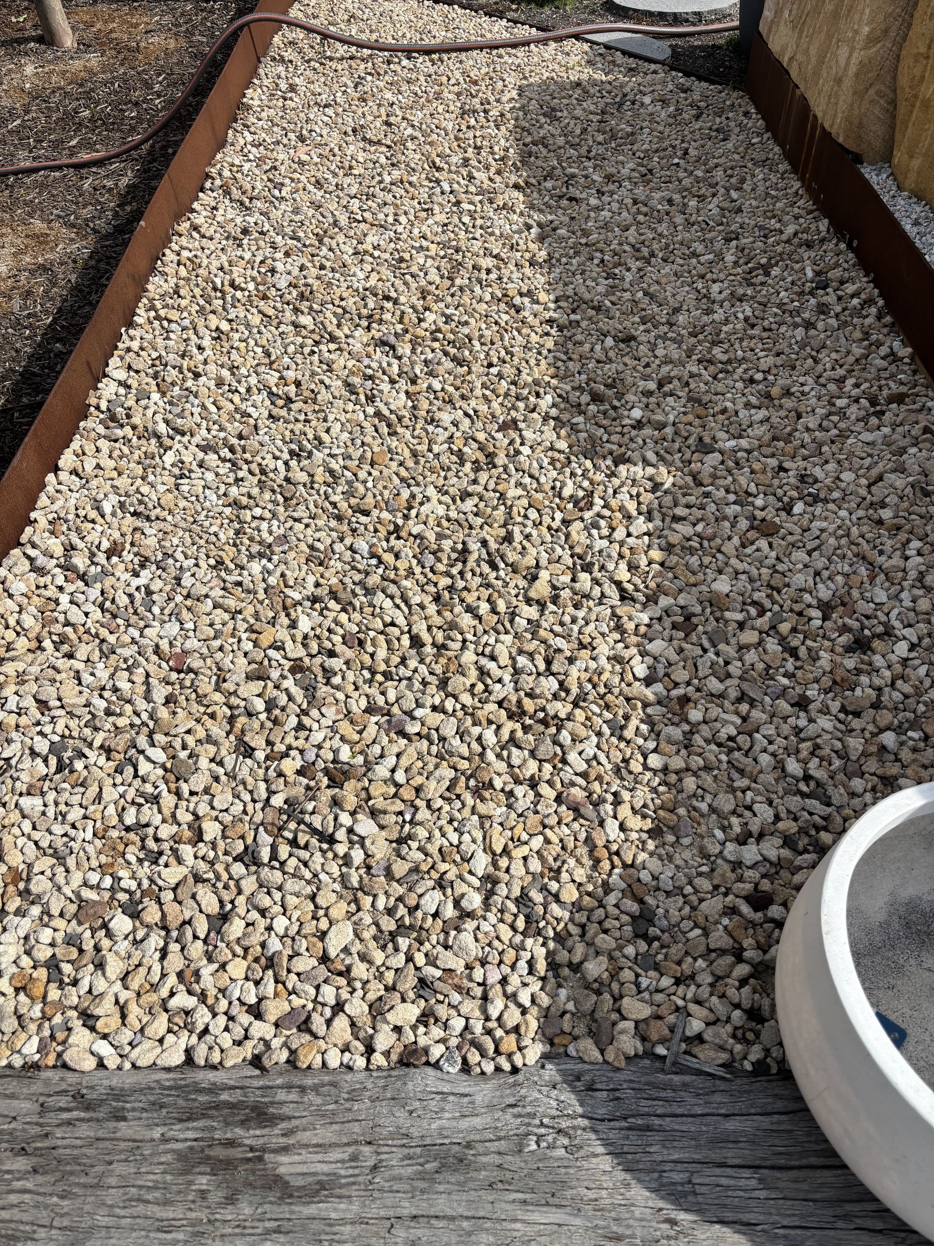 Gravel pathway edged with rusty metal, leading to a light-coloured pot   — Schutz Landscape and Garden Supplies in Tomerong, NSW