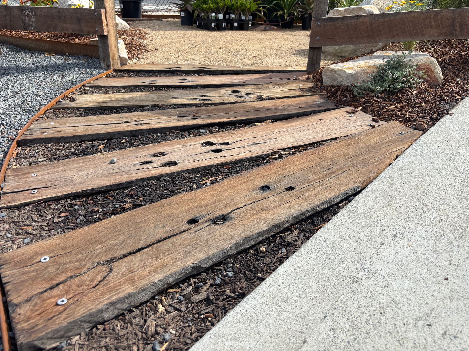 Wooden planks forming a walkway, leading toward a gravel path - Schutz Landscape and Garden Supplies in Tomerong, NSW