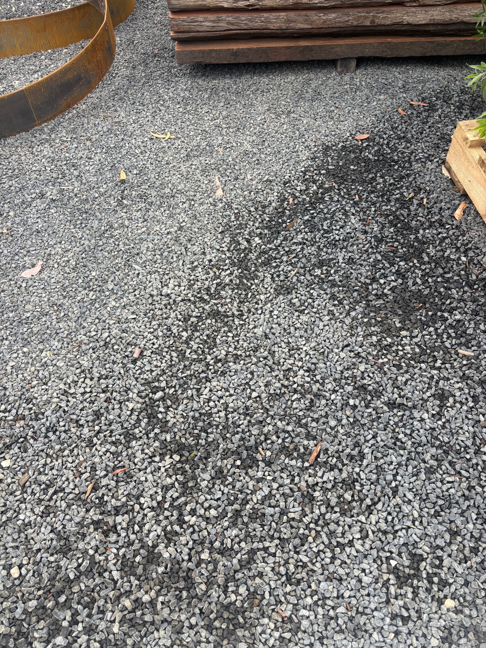 Gravel ground with dark gray stones, wooden planks, and rusted metal rings — Schutz Landscape and Garden Supplies in Tomerong, NSW