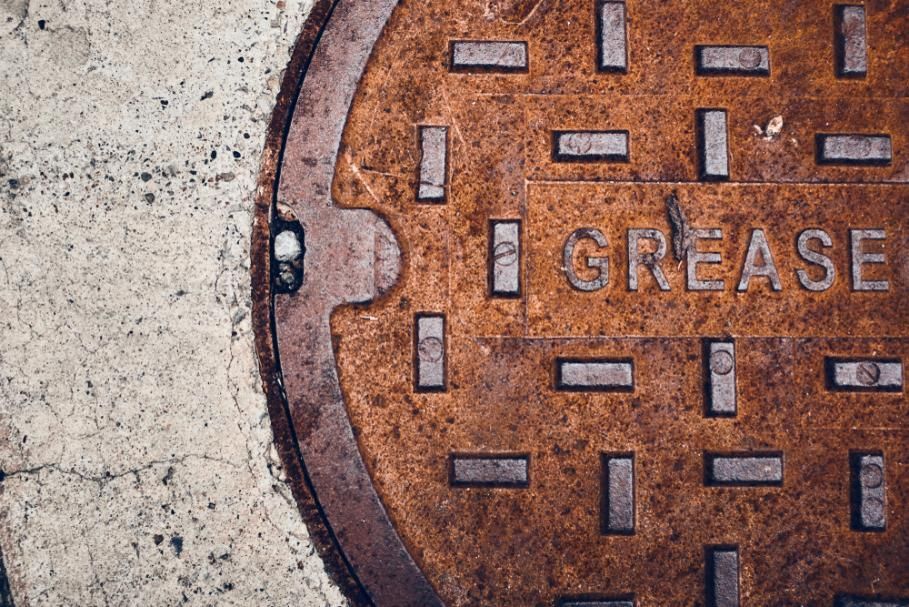 A Rusty Manhole Cover With The Word Grease Written On It — Gympie Septic Pump Outs In Banks Pocket, QLD