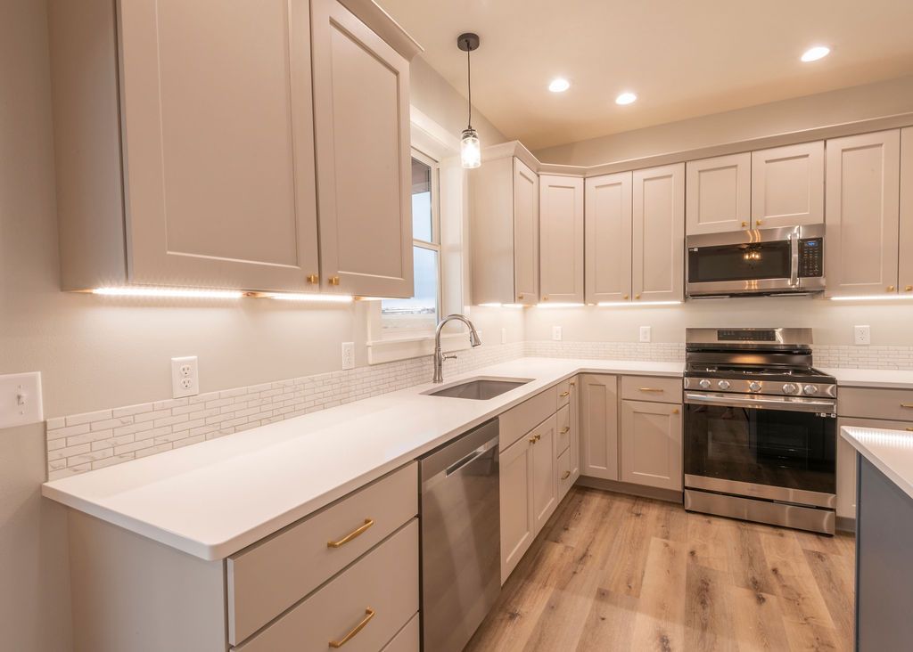 Kitchen with light gray cabinets, white countertops, and stainless steel appliances.