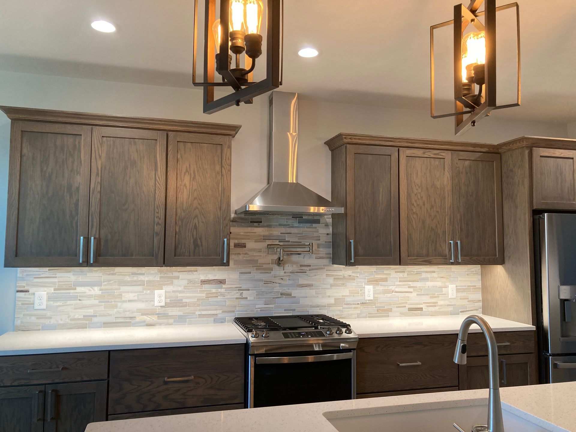 Modern kitchen with dark wood cabinets, stainless steel appliances, and neutral tile backsplash.