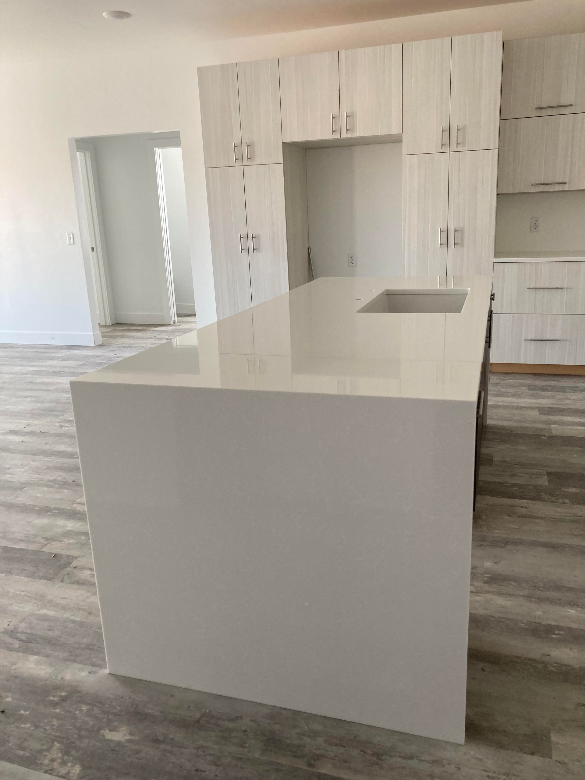 White kitchen island and cabinets in a modern, light-filled room; wooden floor.