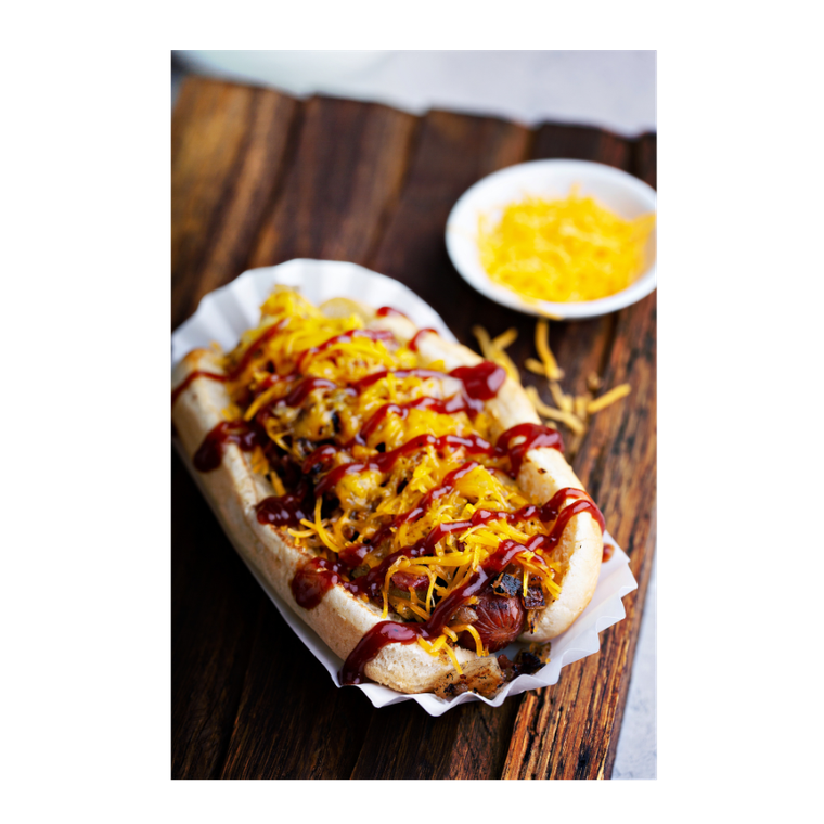 A hot dog with ketchup and cheese on a wooden table.