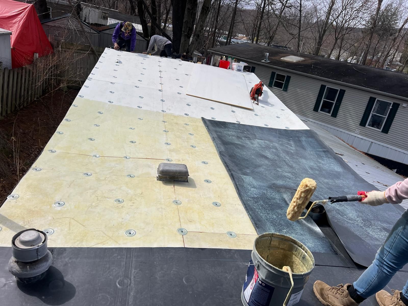 Roof repair in progress: workers installing black and light-colored roofing mater