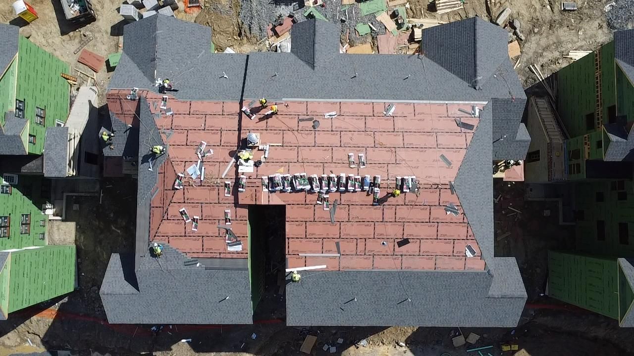 Aerial view of a building under construction, roof partially covered in 
