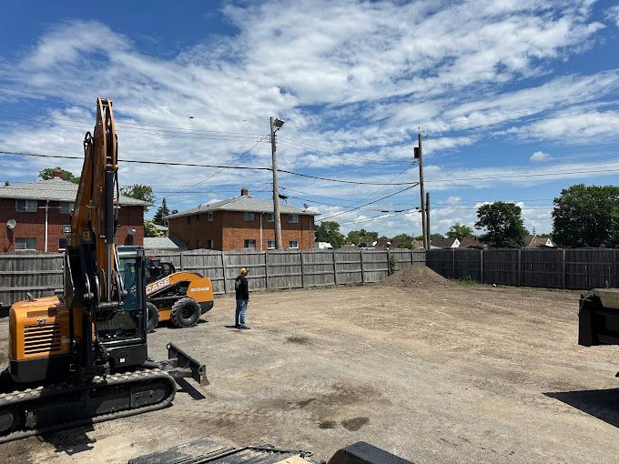 A man is standing in a dirt field next to a construction vehicle.