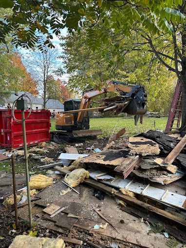 A large excavator is demolishing a house in a yard.