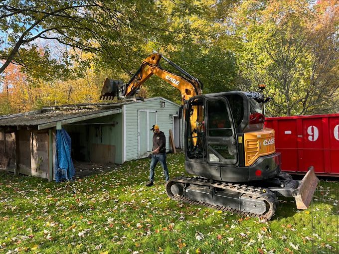 A man is standing next to a small excavator.