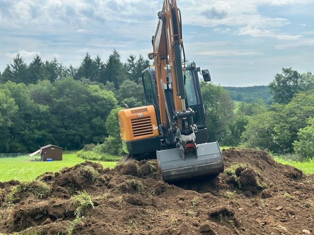 An excavator is digging a hole in the dirt in a field.