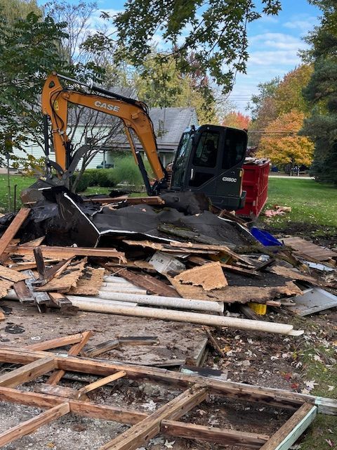 An excavator is demolishing a house in a yard.
