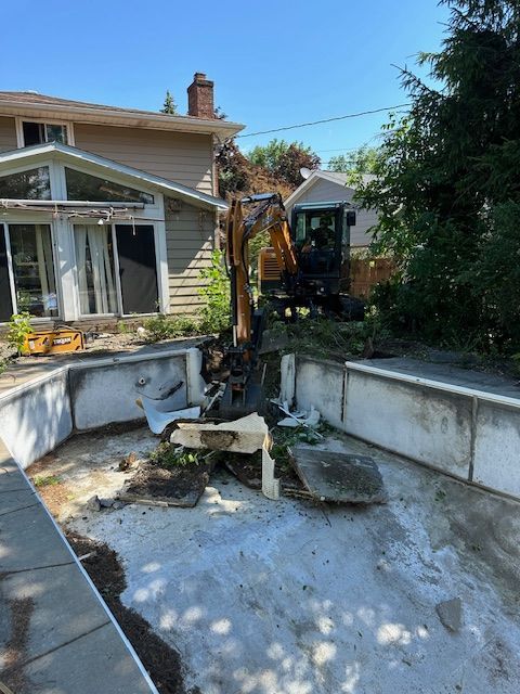 An excavator is working on a swimming pool in front of a house.