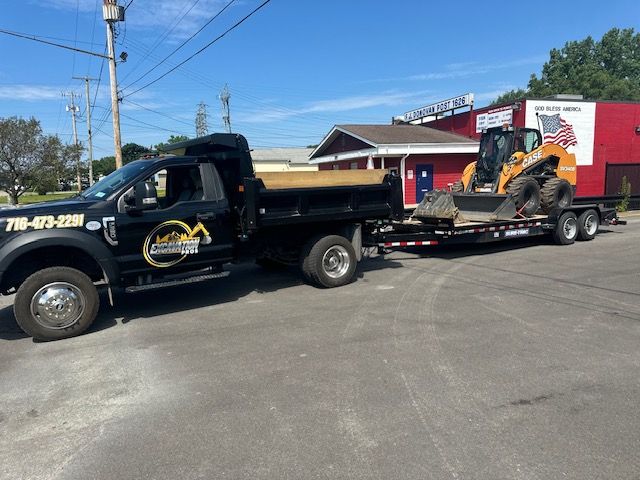 A dump truck is towing a bulldozer on a trailer.