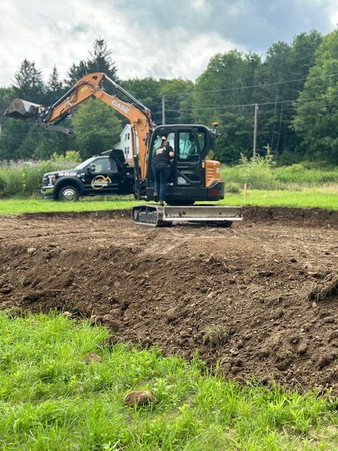 A man is standing next to an excavator in a field.