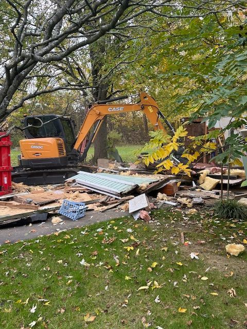 An excavator is demolishing a house in a yard.