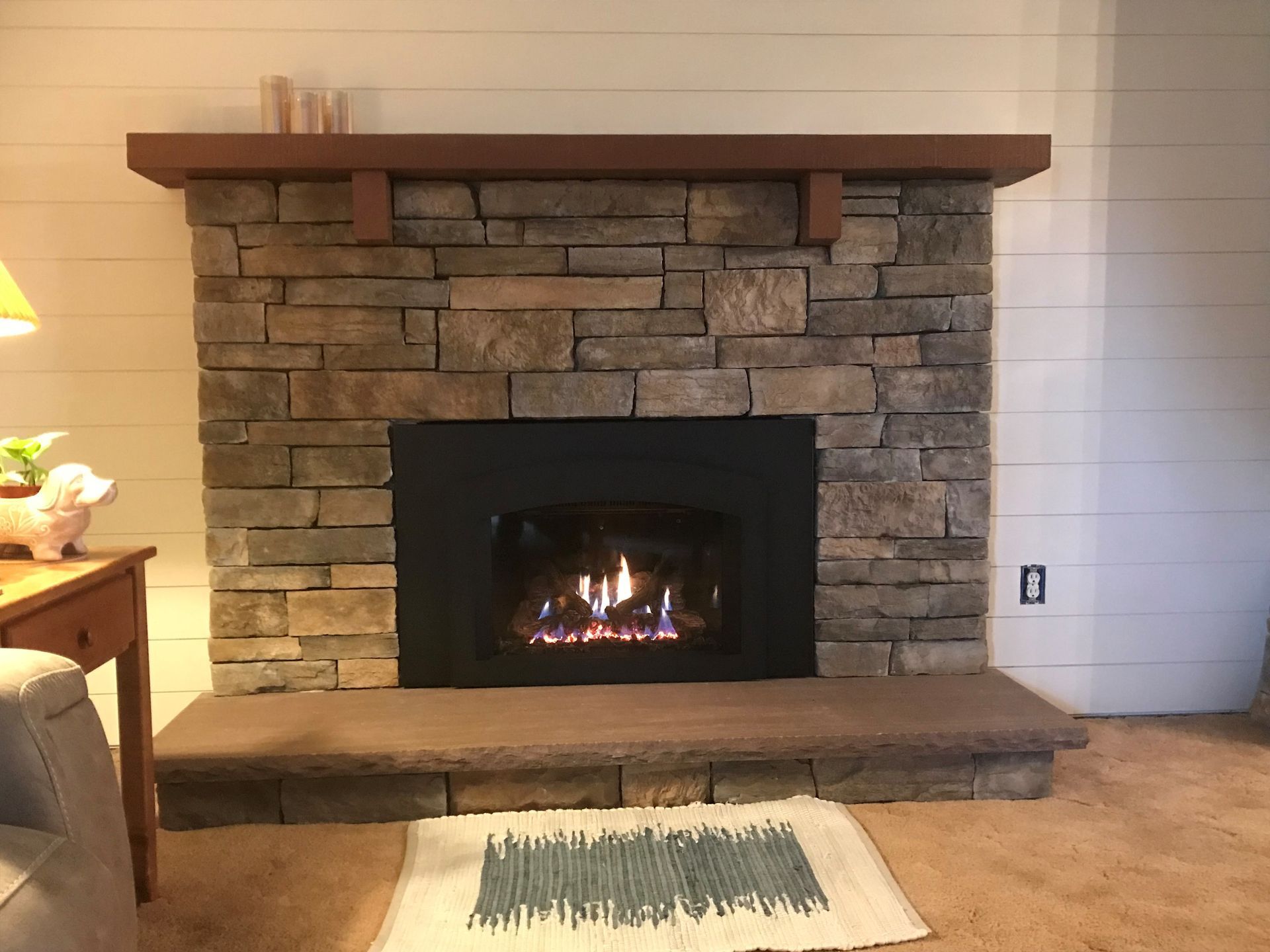A living room with a fireplace and a rug on the floor.