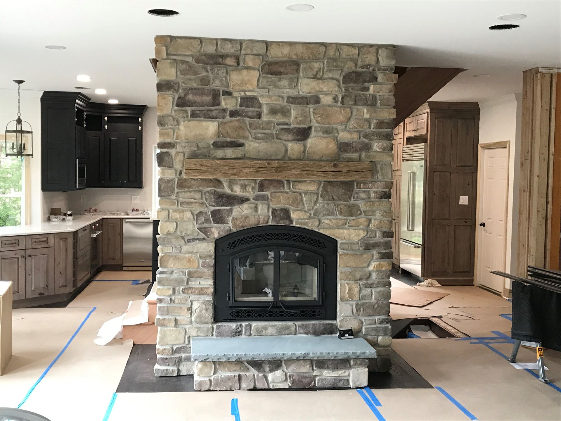 A stone fireplace in a living room with a black door.