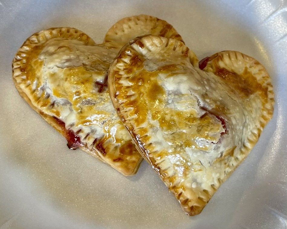 Two heart shaped pastries are on a paper plate.
