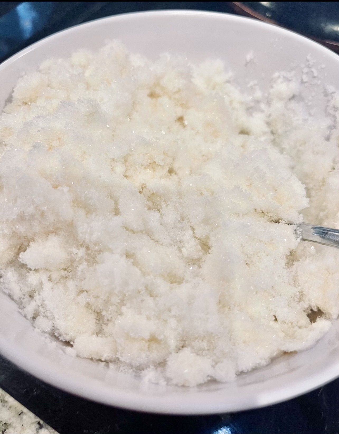 A bowl of white rice with a spoon in it