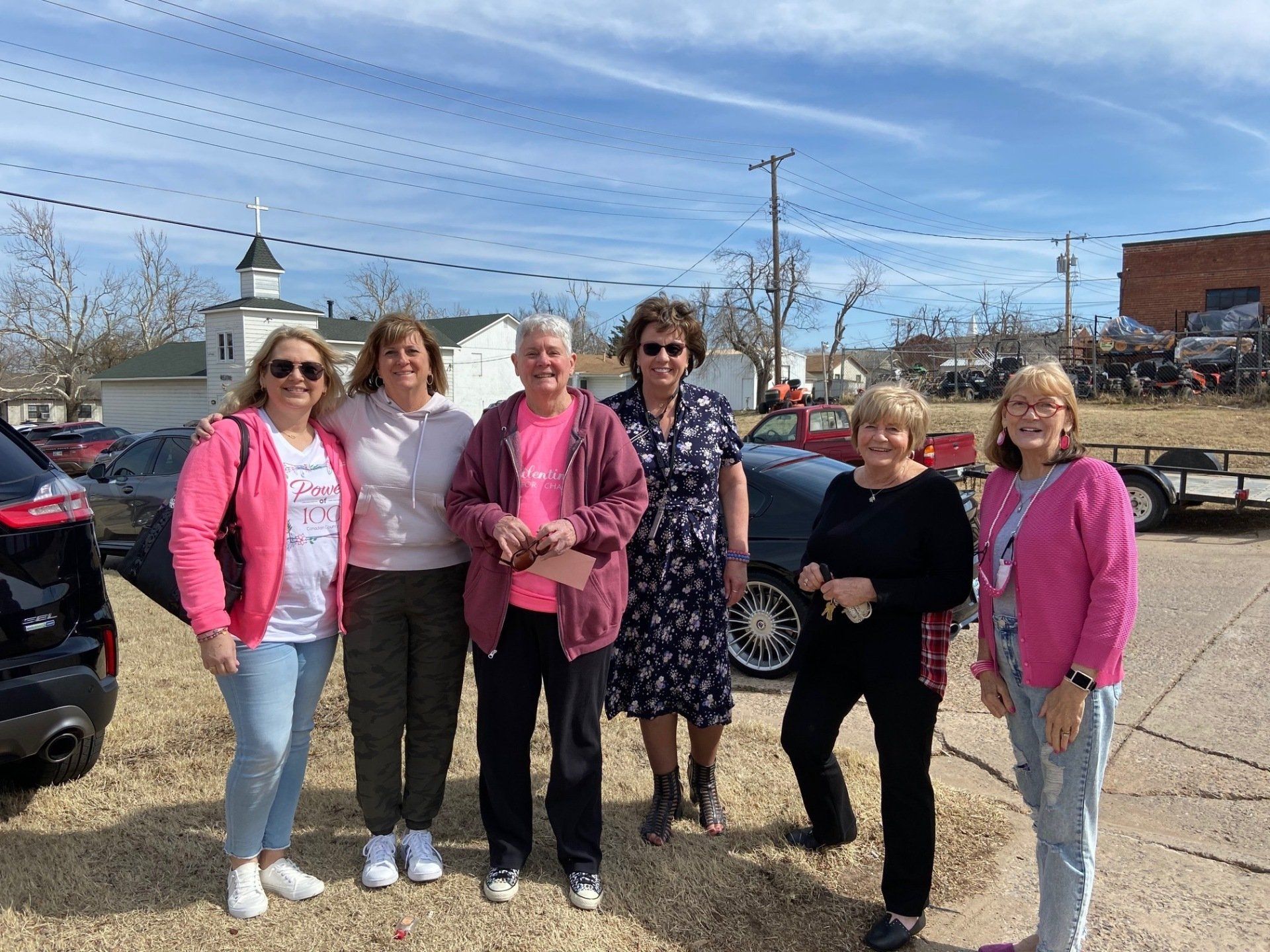 A group of women are standing next to each other in a parking lot.