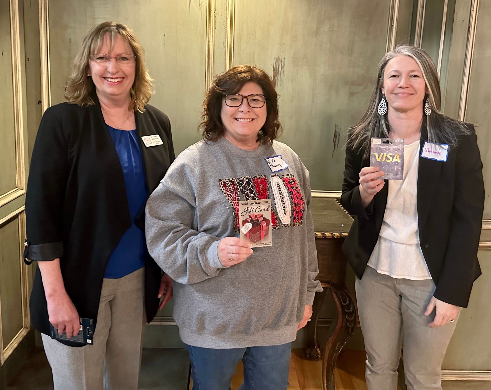 Three women are standing next to each other in a room.