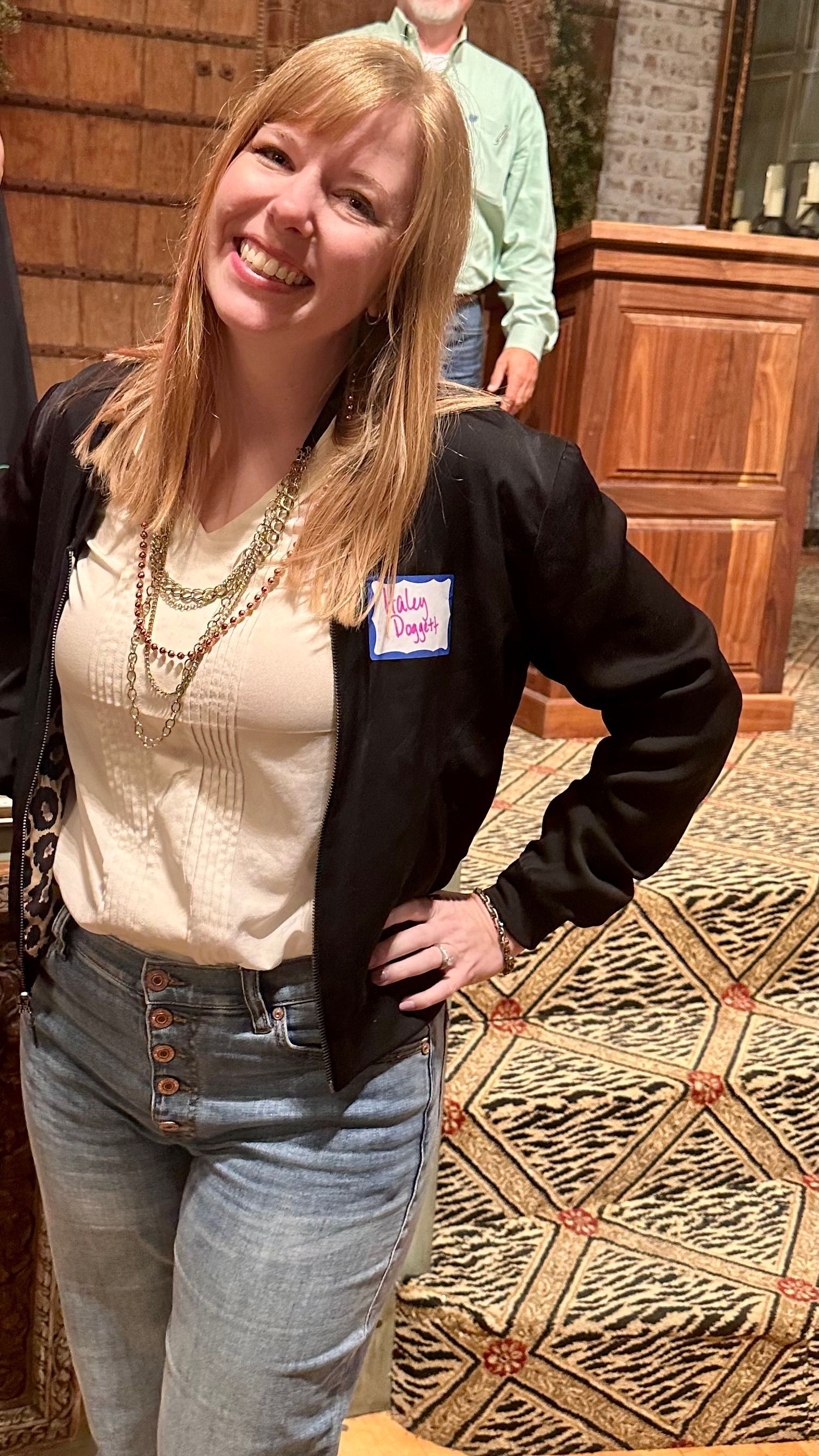 A woman is standing in a room with her hands on her hips and smiling.