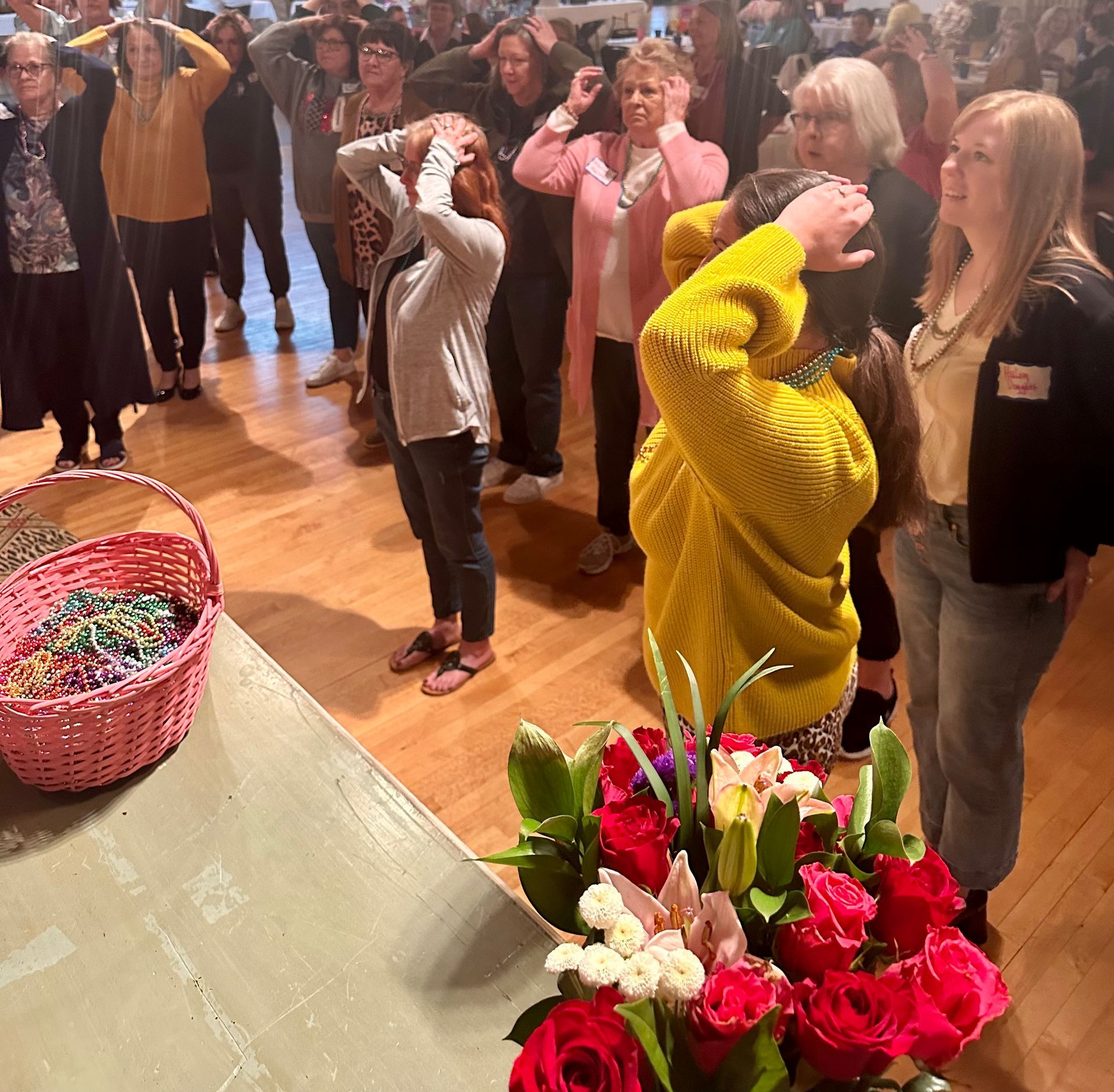 A group of people standing around a table with flowers and a basket of beads