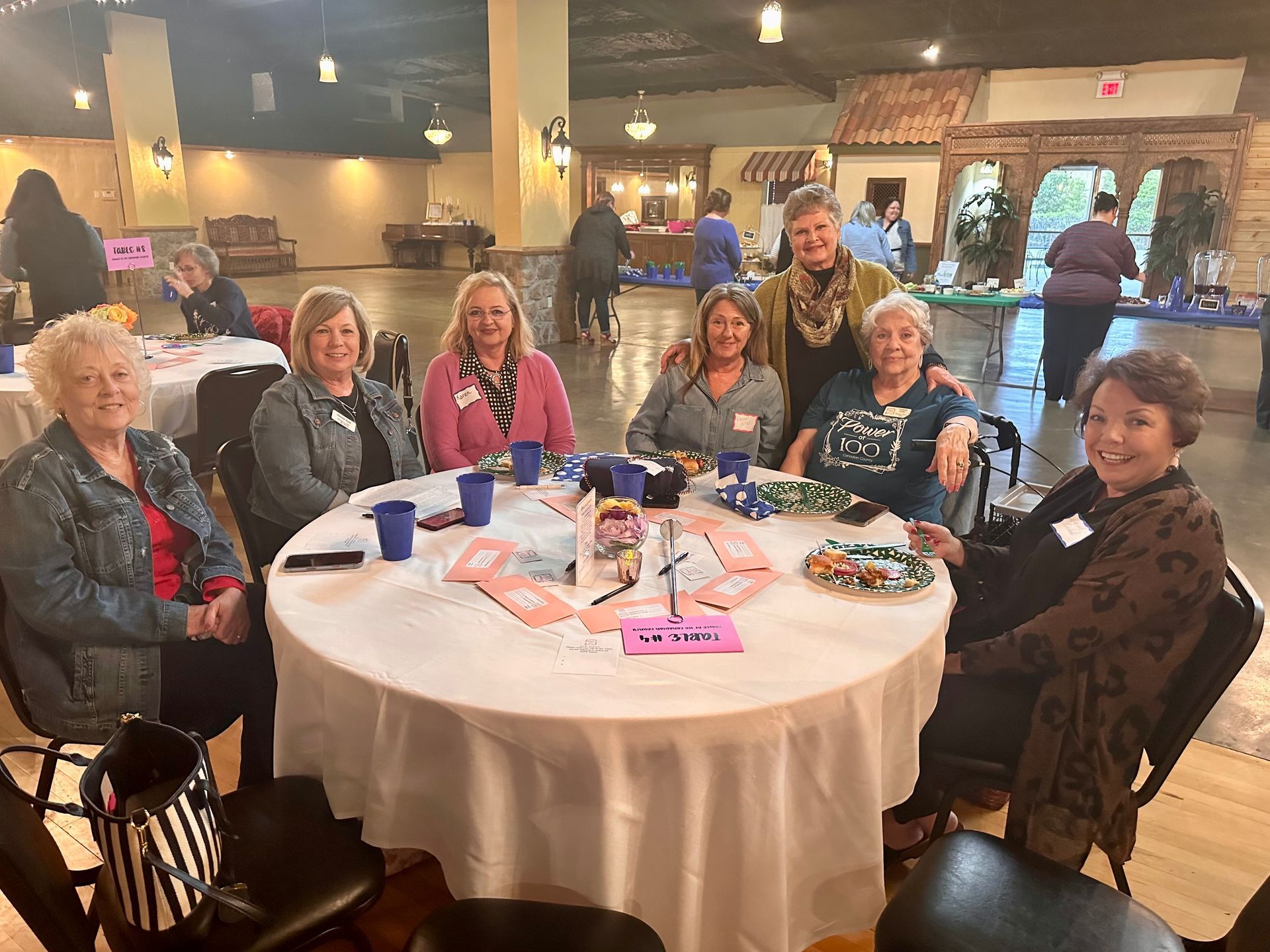 A group of older women are sitting around a round table.