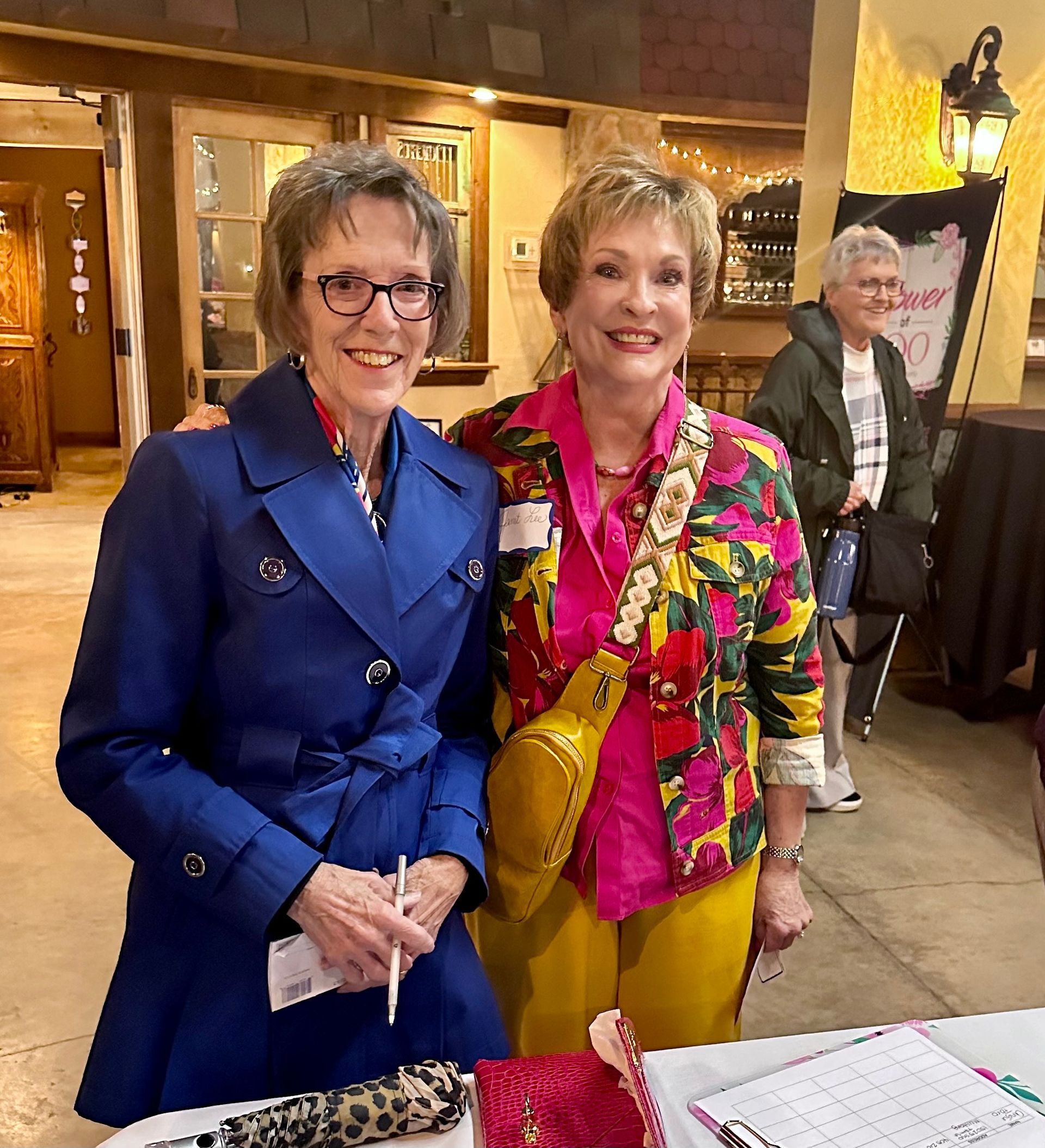 Two women are posing for a picture while standing next to each other in a room.