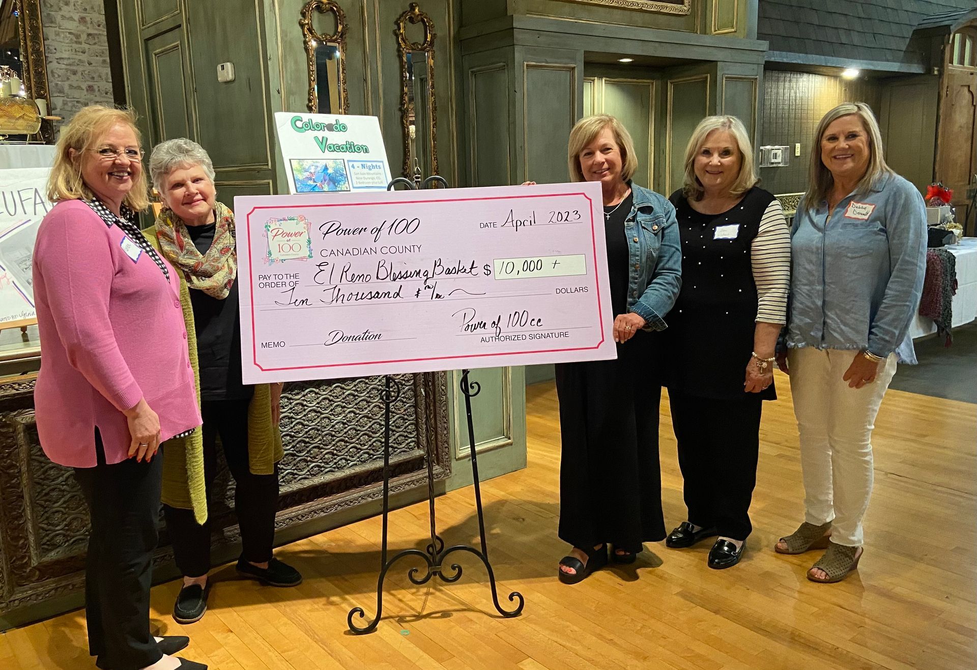 A group of women are standing next to each other holding a large check.