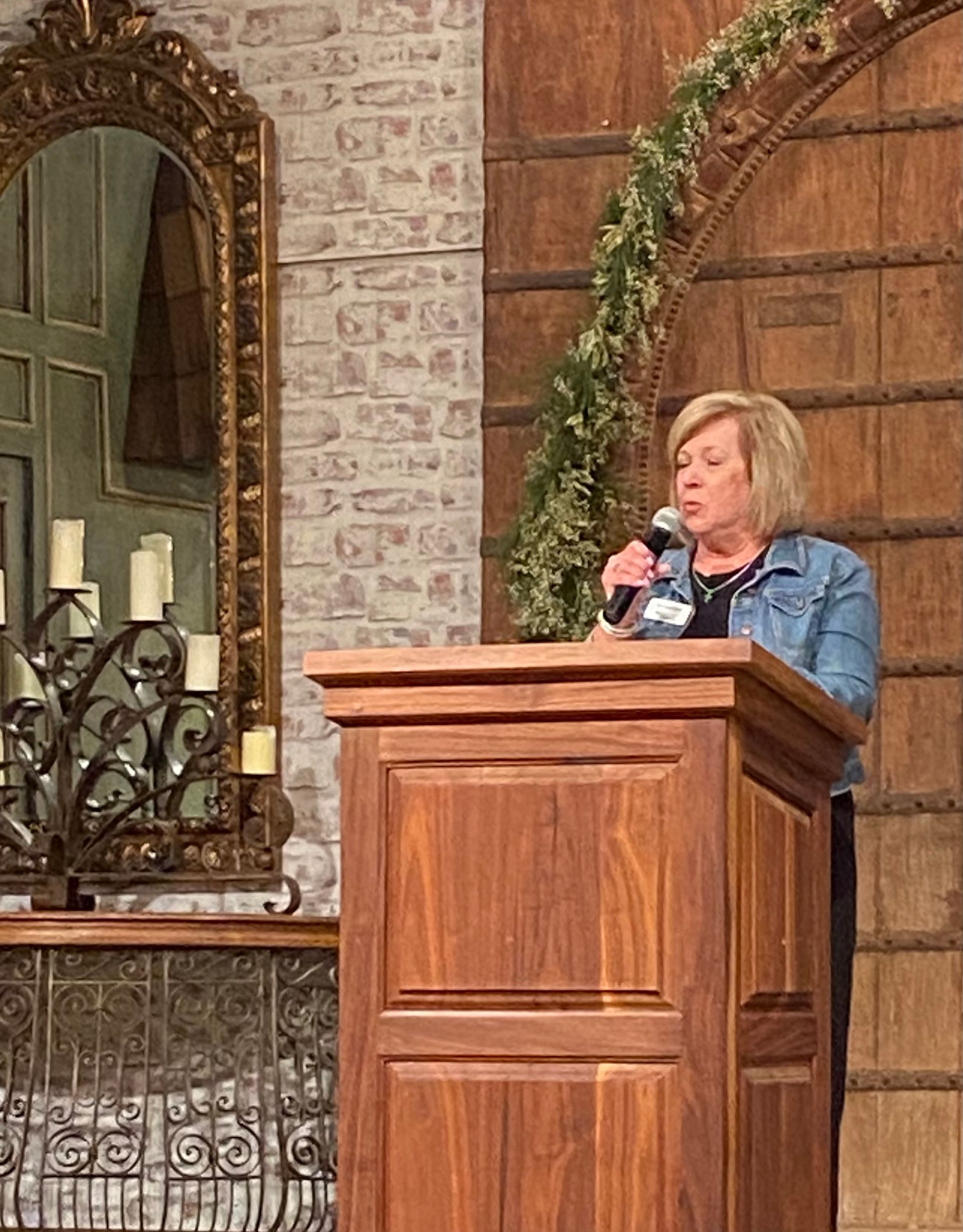 A woman is standing at a podium holding a microphone.