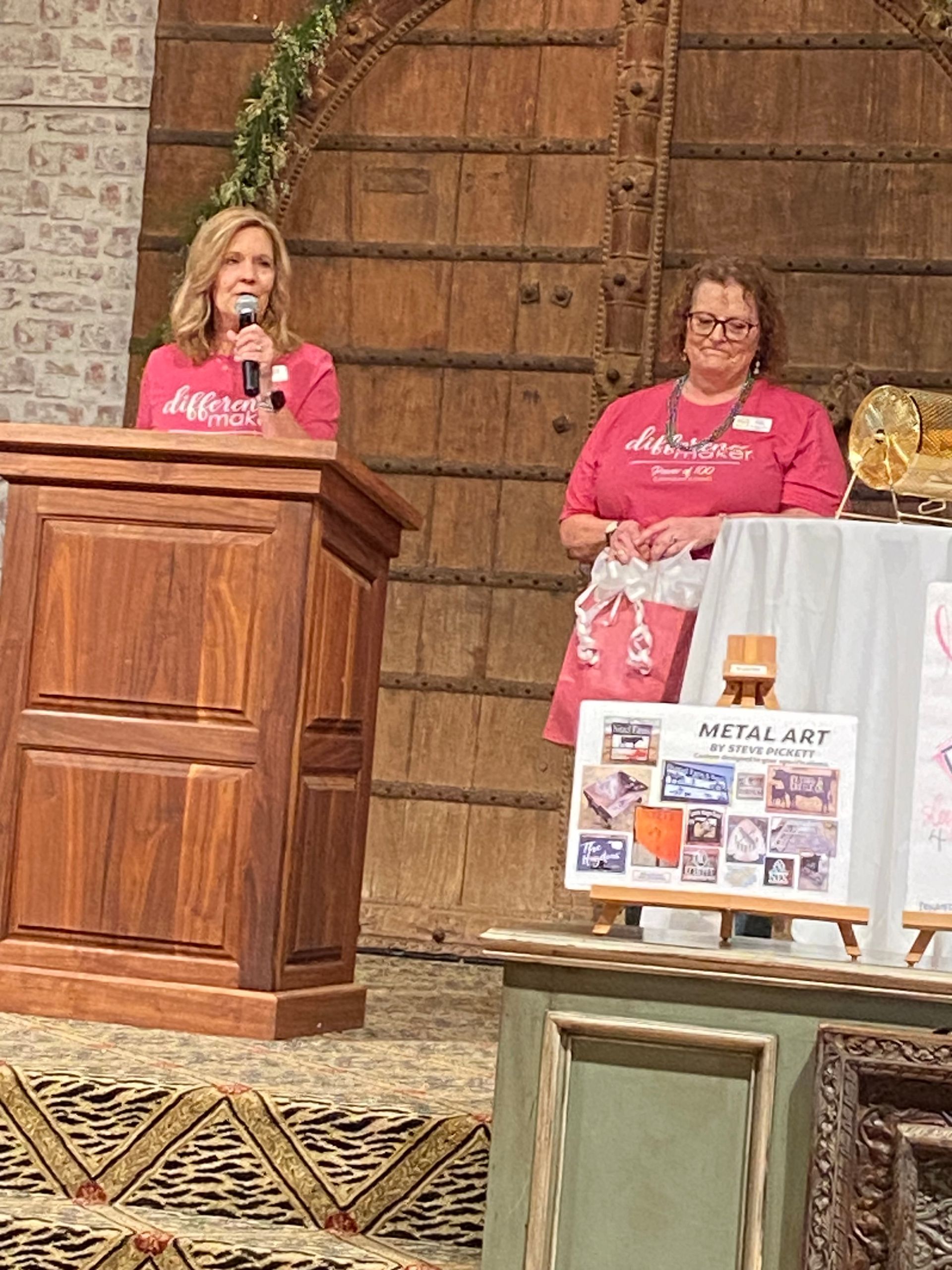 Two women are standing at a podium talking into microphones.