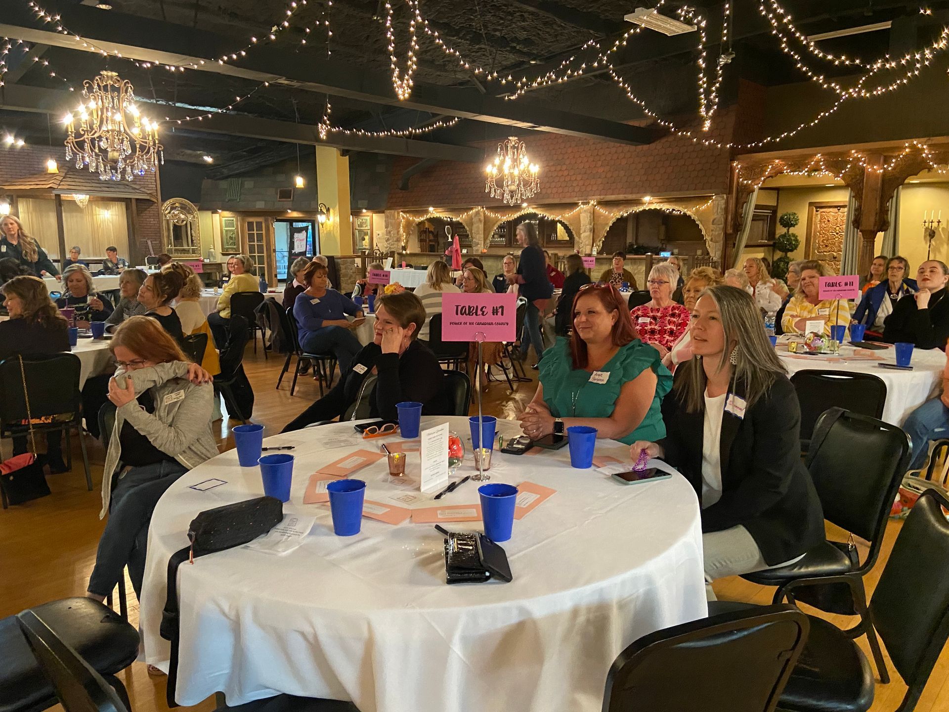 A group of people are sitting at tables in a large room.