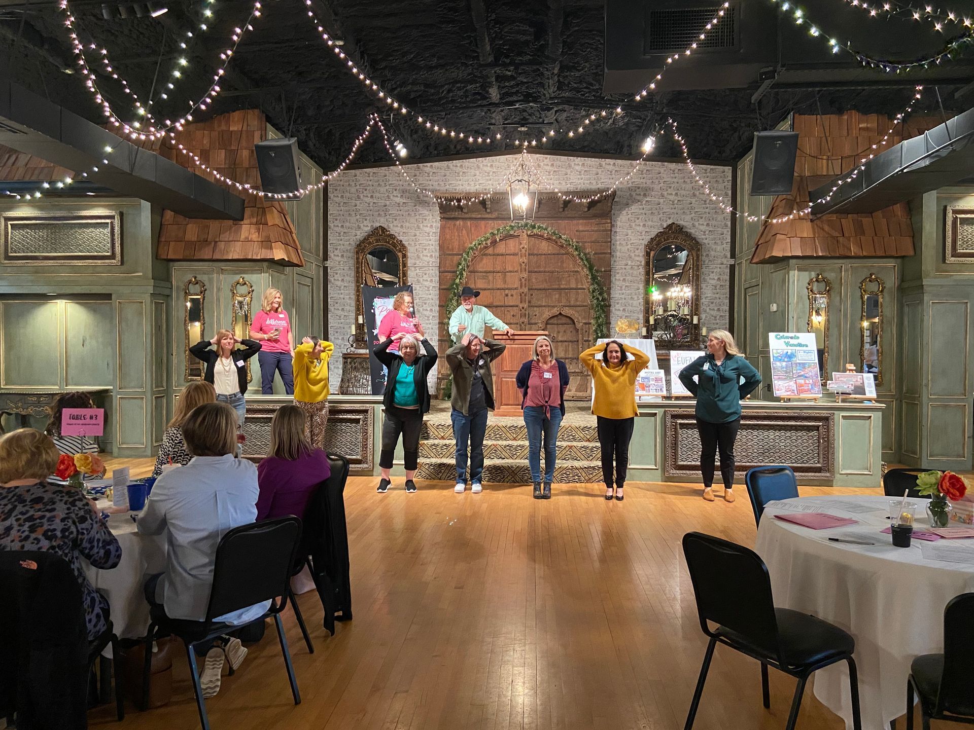A group of people are standing on a dance floor in a room.
