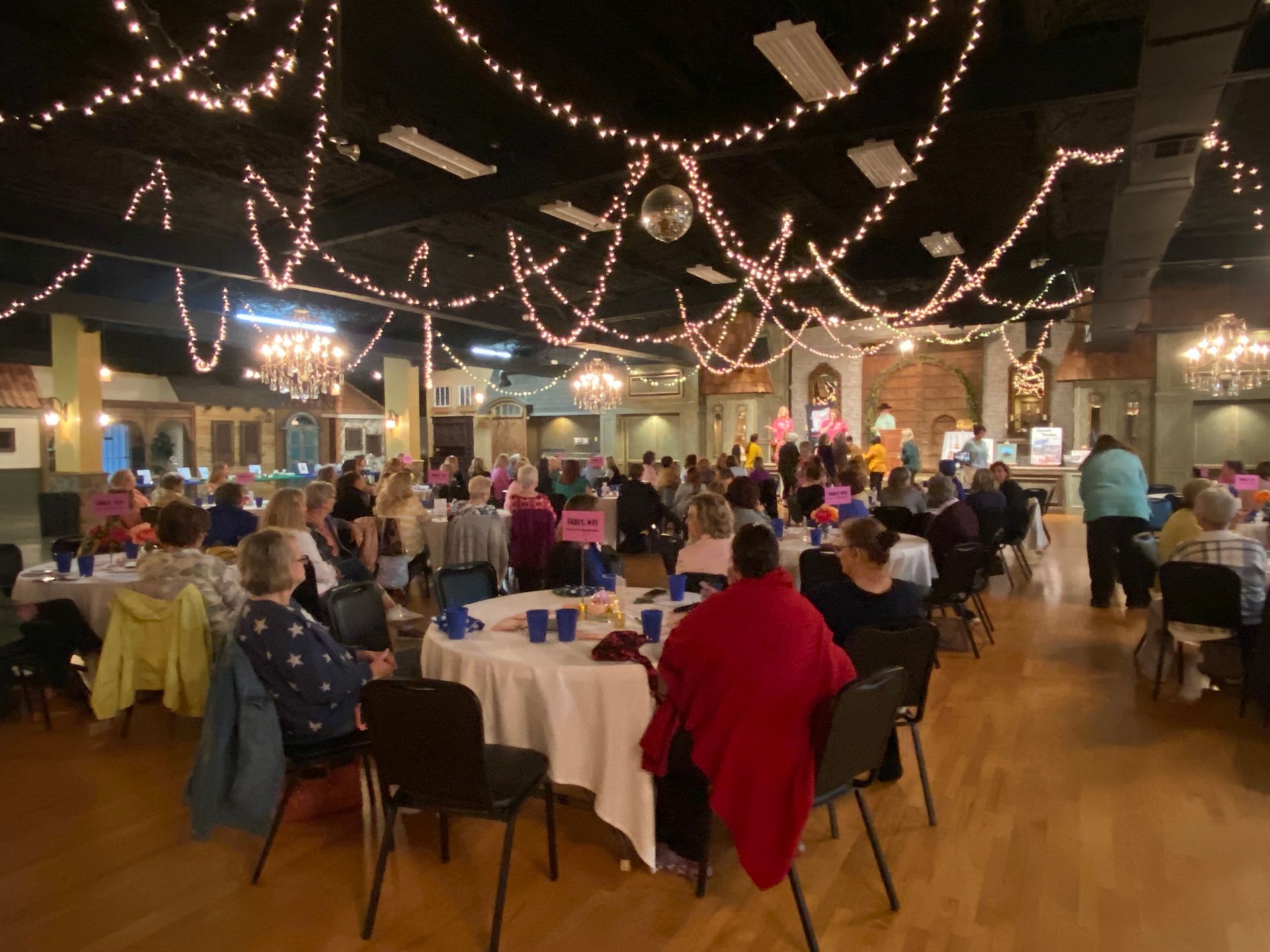 A large group of people are sitting at tables in a large room.