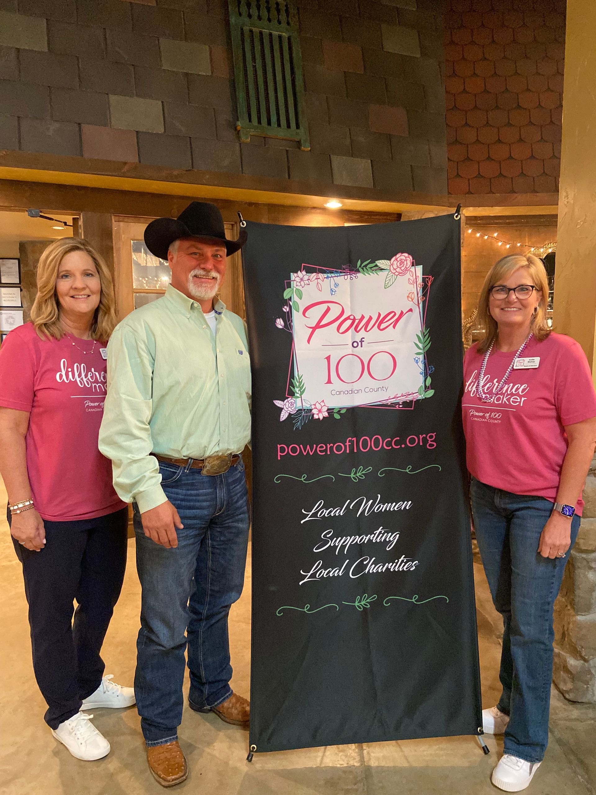A man and two women are standing next to a sign that says power of 100.