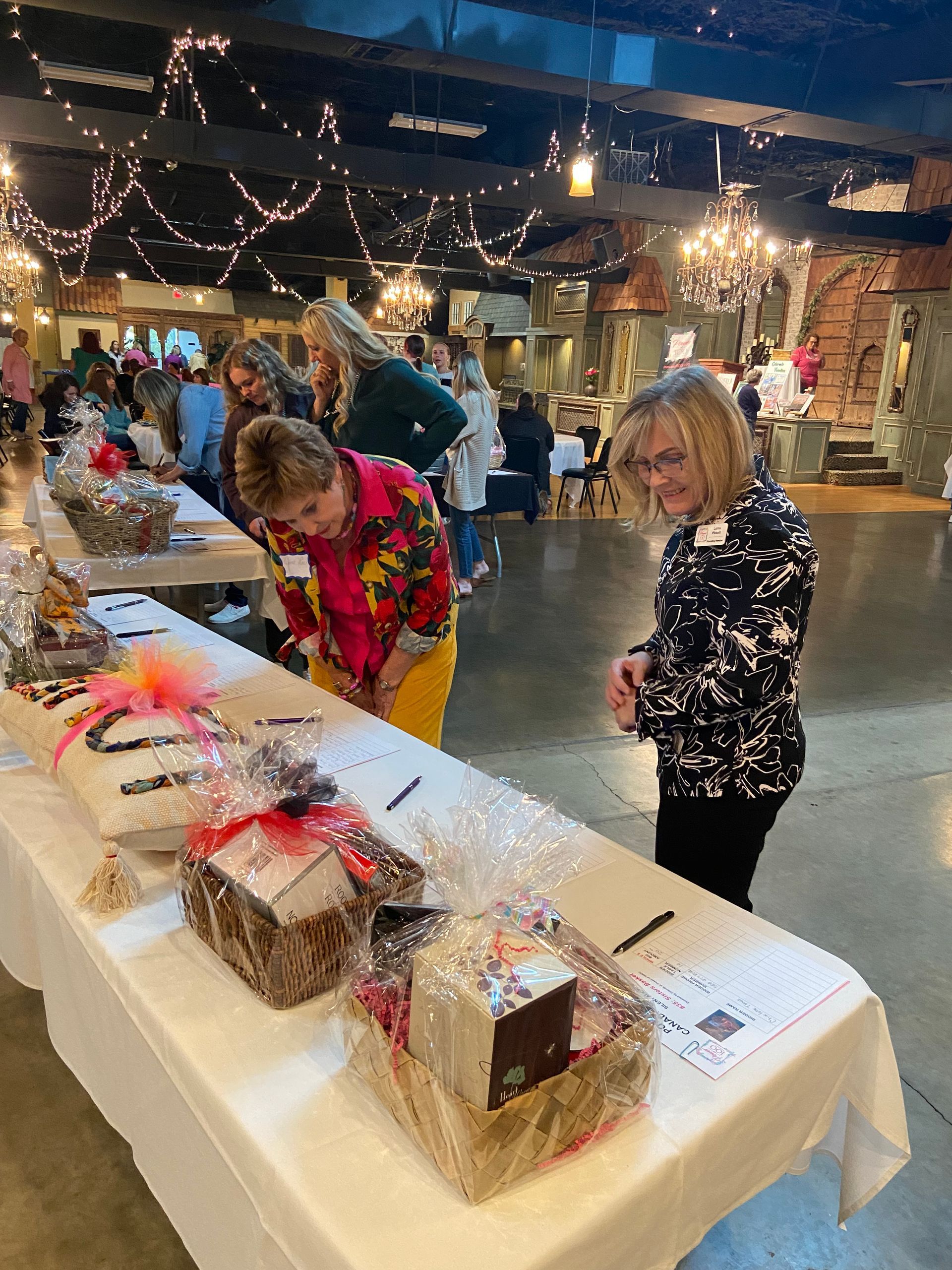A group of people are standing around a table with baskets on it.