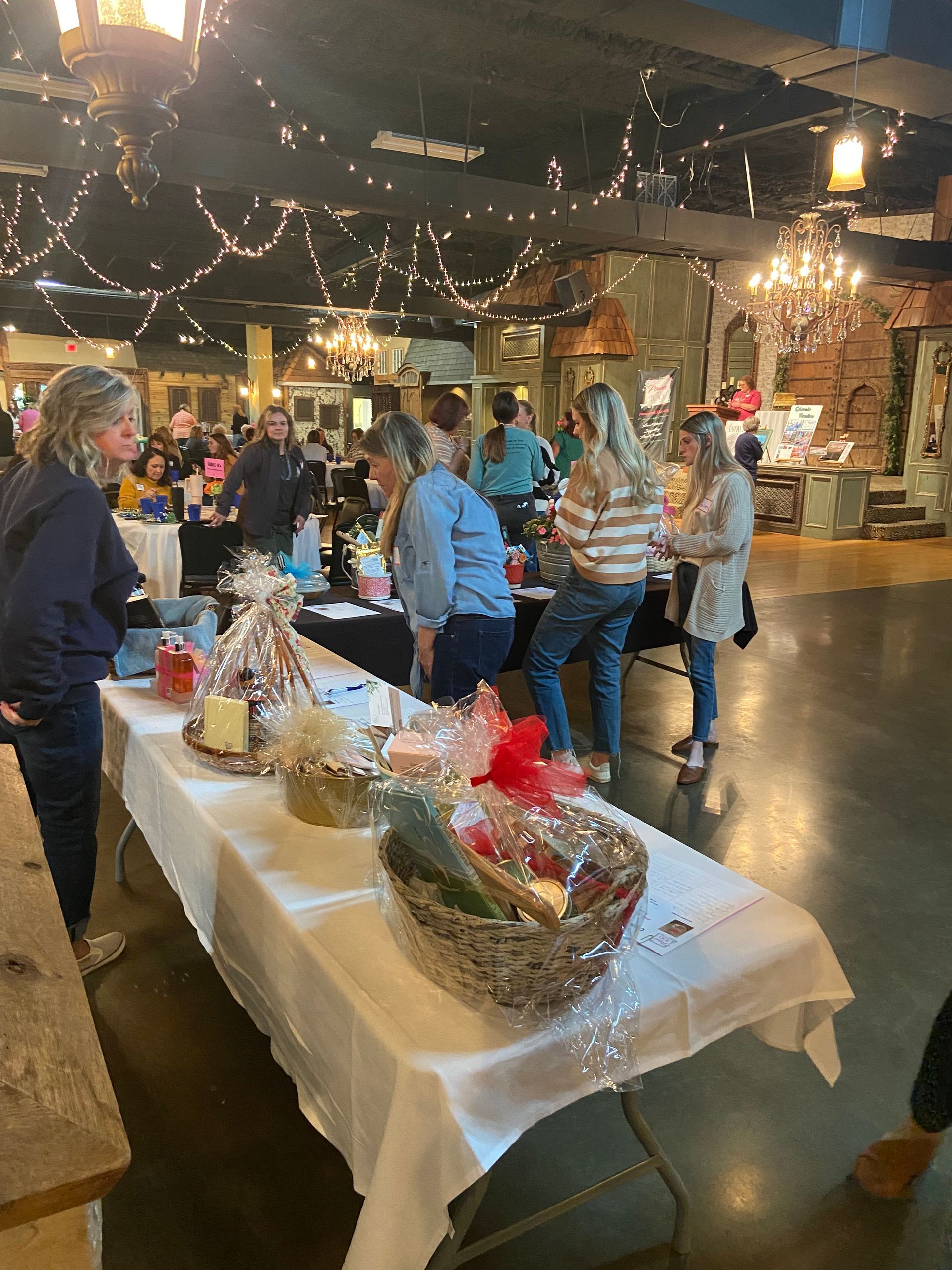 A group of people are standing around tables in a room.