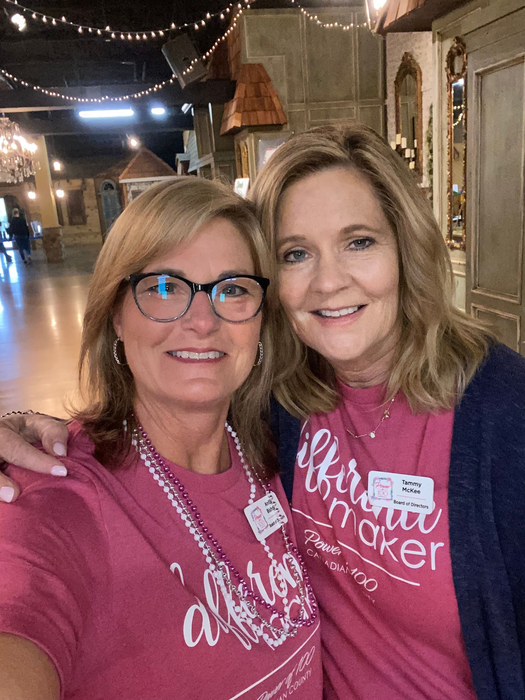 Two women wearing pink shirts are posing for a picture.